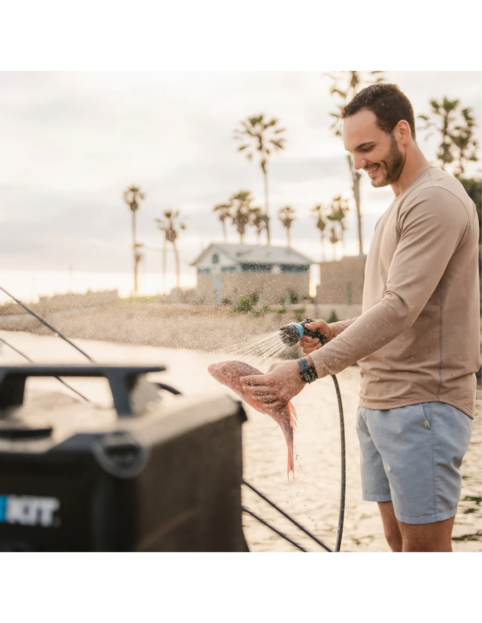 RinseKit Cube portable shower rinsing fish at beach after fishing