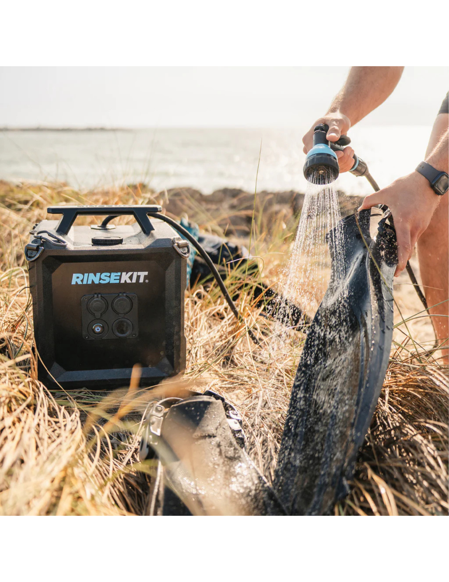 RinseKit Cube portable shower washing sandy swim fins near the beach