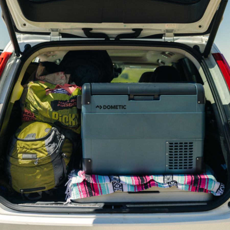 Dometic cooler in a car trunk with bags and blankets