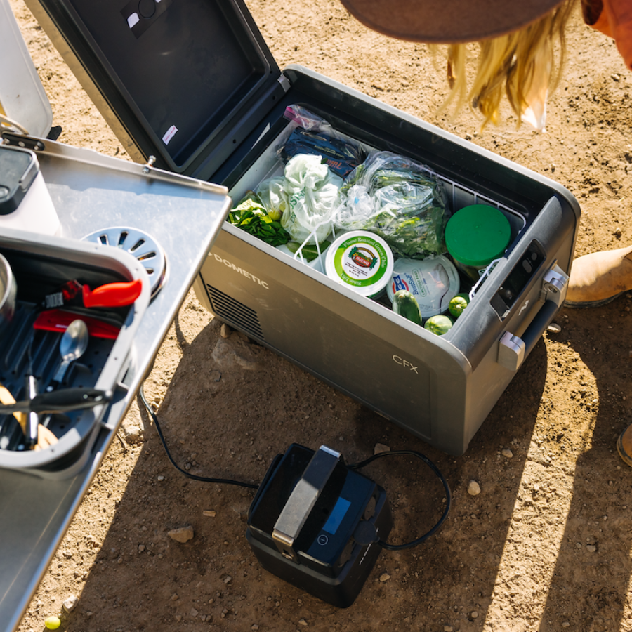 Portable refrigerator with food items on a dirt ground