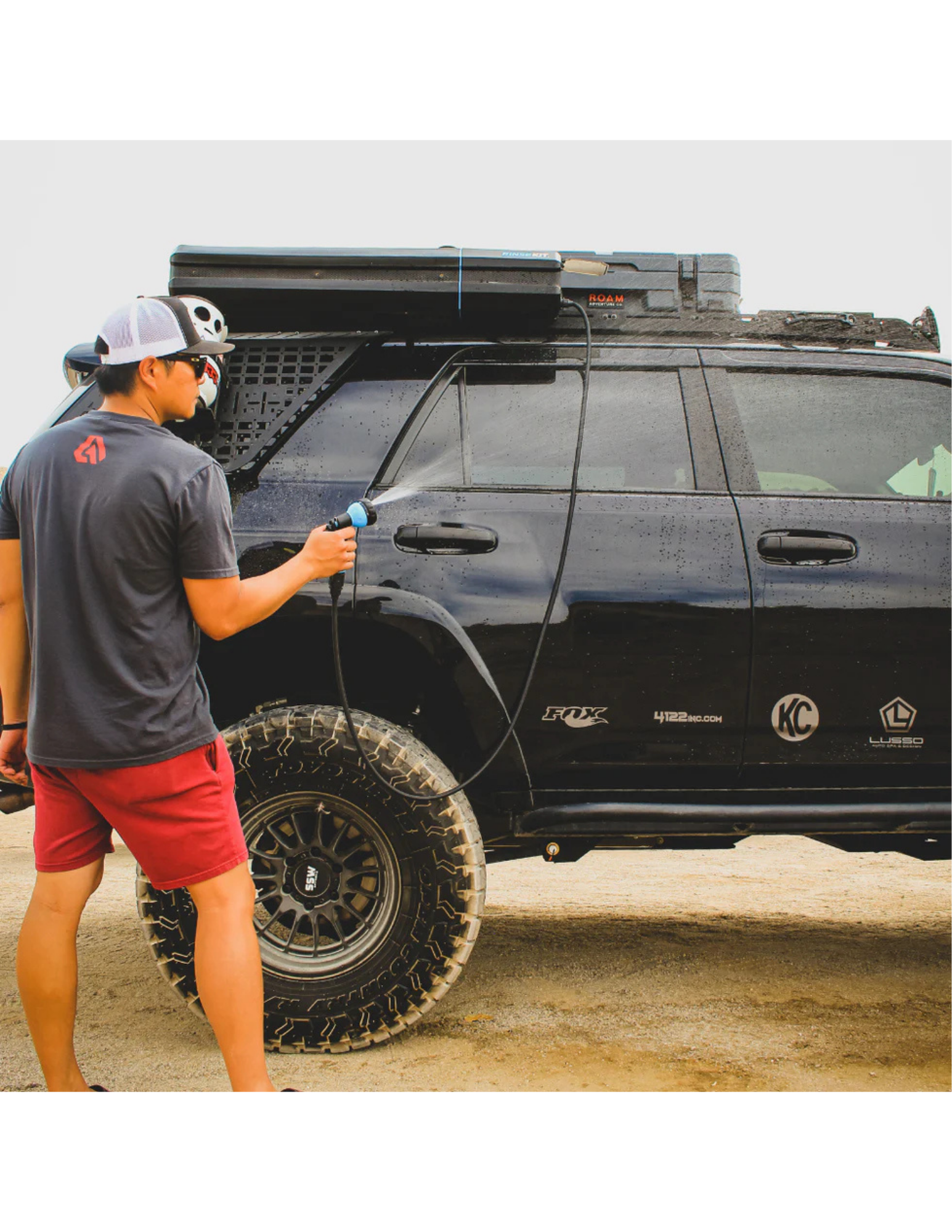 RinseKit portable rack shower spraying black off-road SUV after camping or trail use