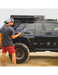 RinseKit portable rack shower spraying black off-road SUV after camping or trail use